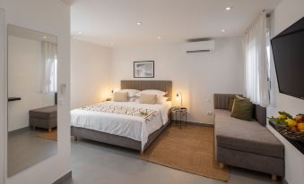 a modern bedroom with a large bed , white walls , and a gray couch , along with two nightstands on either side of the bed at Waterman Beach Village