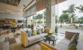a modern lounge area with yellow and white couches , a coffee table , and large windows at Navada Beach Hotel