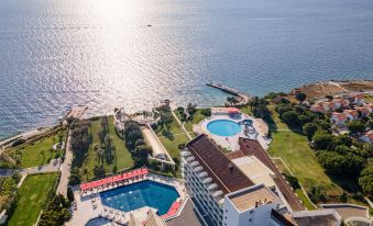 a large resort with multiple buildings , including a swimming pool and a beach , situated near the ocean at Grand Hotel Ontur Cesme