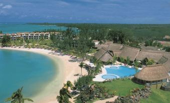 a beautiful beach resort with a swimming pool surrounded by lush greenery and a clear blue ocean at Lux* Grand Gaube