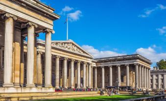 a large , white building with columns and a grassy area in front of it , under a clear blue sky at The Hide London