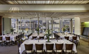 a large dining room with multiple tables and chairs arranged for a group of people at Novotel Queenstown Lakeside