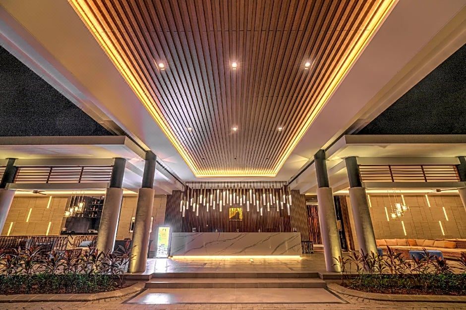 a modern hotel lobby with wooden ceiling , stone columns , and a marble reception desk under the eaves at Mambruk Hotel & Convention