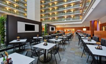 a large , modern hotel lobby with multiple dining tables and chairs arranged for guests to sit and enjoy their meal at Embassy Suites by Hilton Chicago Downtown Magnificent Mile