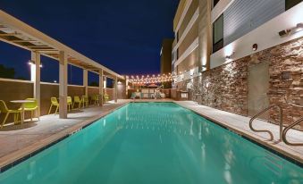 an outdoor swimming pool surrounded by a building , with several chairs and tables placed around it at Home2 Suites by Hilton Tracy