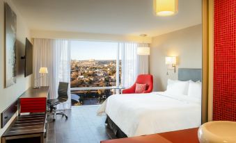 a modern hotel room with a large bed , white bedding , and a view of the city at Fiesta Inn Express Queretaro Constituyentes