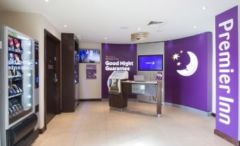 "a hotel lobby with a purple wall and a reception desk , featuring the words "" good night guarantee .""." at Premier Inn Honiton