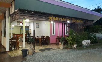 A restaurant offers outdoor seating with tables and chairs on the sidewalk and in an adjacent outdoor area at Punyaporn Resort