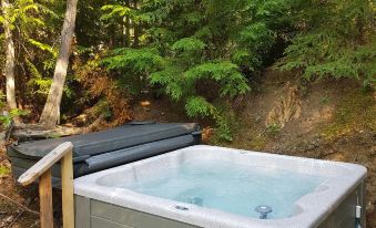 a wooden deck with a hot tub surrounded by lush greenery , providing a serene and relaxing atmosphere at Woodland Cabins