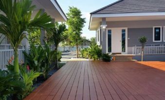 a wooden deck leading to a house surrounded by lush greenery , including palm trees and bushes at Rongsang Resort