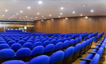 an empty auditorium with rows of blue chairs and wooden walls , under a bright light at Grand Hotel Salerno