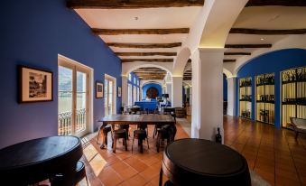a modern , spacious room with blue walls and wooden beams , containing multiple dining tables , couches , and benches at The Vintage House - Douro