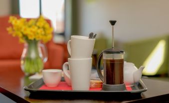 a dining table with a variety of cups and bowls on it , including coffee and tea at YHA Blaxhall - Hostel