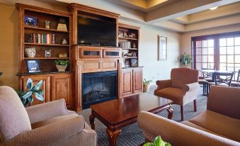 a cozy living room with wooden furniture , including a fireplace , chairs , and a television at Franklin Inn and Suites
