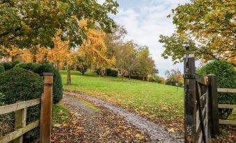 a wooden gate with a metal fence on the left , leading to a grassy field and a house in the distance at Travelodge Scotch Corner Skeeby