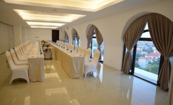 a long table with white chairs and blue water bottles is set up in a room with large windows at Westlake Hotel & Resort Vinh Phuc
