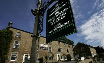 a sign for the punch bowl inn , a historical building with various characters and locations , near a street and buildings at The Punch Bowl Inn