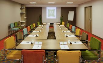 a conference room set up for a meeting , with multiple chairs arranged in rows and a projector on the wall at Ibis Styles Chaumont Centre Gare