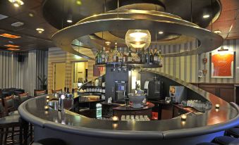 a bar with a circular counter and several bottles of alcohol on display , creating an inviting atmosphere at Fletcher Parkhotel Val Monte