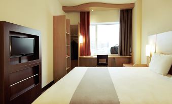 a hotel room with a king - sized bed , a flat - screen tv , and a window overlooking the city at Ibis Brussels Airport