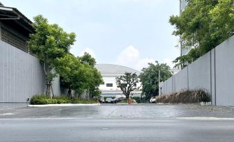 There is an empty parking lot along a street lined with trees and buildings at Orion Hotel & Residence