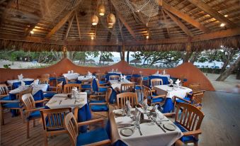 a large dining room with multiple tables and chairs , some of which are covered in blue tablecloths at Sunscape Puerto Plata All Inclusive