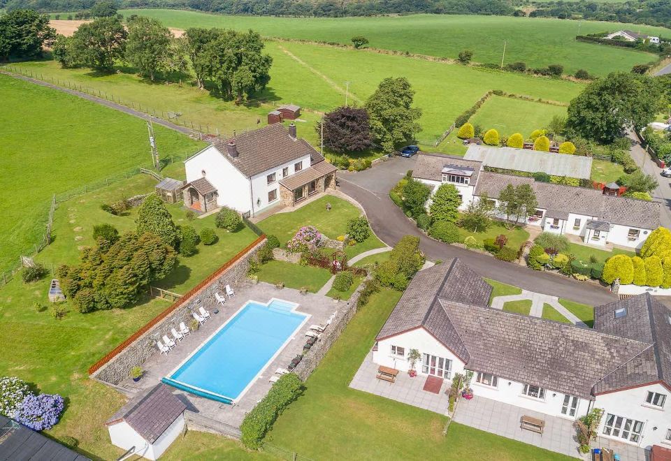 a bird 's eye view of a large house with a pool and surrounding green fields at Trenewydd Farm Holiday Cottages