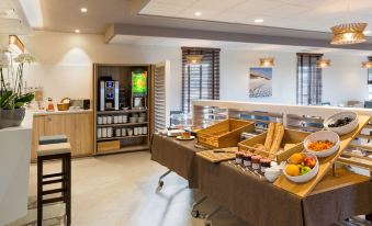 a dining area with a buffet table filled with various food items , including sandwiches , fruits , and desserts at Best Western Hotel le Semaphore