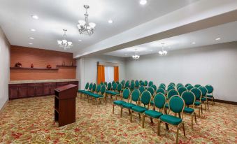 a conference room with rows of green chairs arranged in a semicircle , and a podium at the front of the room at La Quinta Inn & Suites by Wyndham Houston Channelview