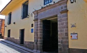 a cobblestone street in a small town , with a yellow building on the left side of the street at Novotel Cusco