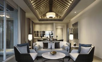 a modern living room with a large couch , two chairs , and a dining table in the background at Banyan Tree Krabi