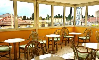 an empty restaurant with several tables and chairs , all facing the window , and a view of the city outside at Hotel Rio Sanremo