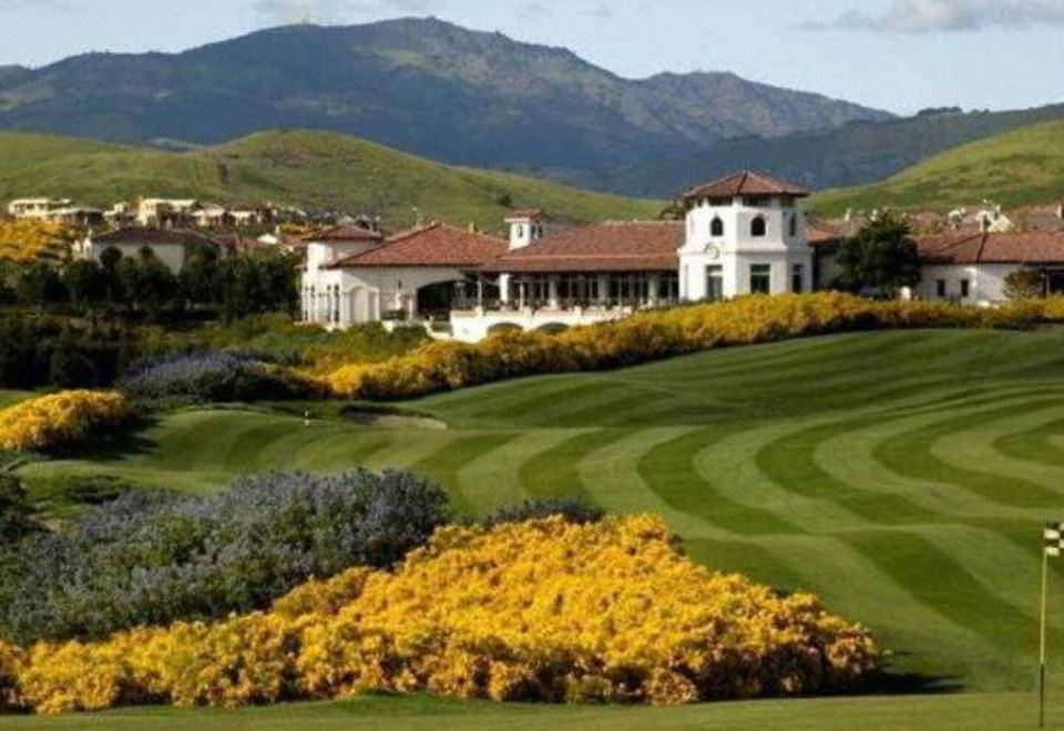 a beautiful golf course with a large white building in the background and yellow flowers surrounding the green grass at Courtyard Pleasanton