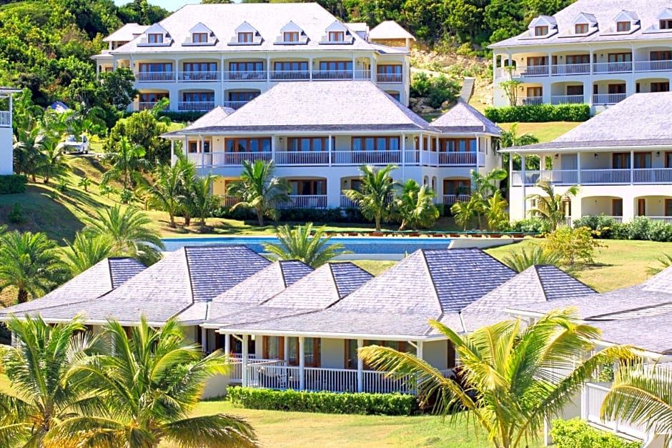 a resort with multiple buildings , a pool , and palm trees is shown from an aerial view at Residences at Nonsuch Bay Antigua - Room Only - Self Catering