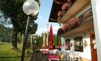 a patio area with tables , chairs , and umbrellas is shown next to a building with flower boxes at Berghof