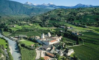 aerial view of a castle surrounded by green fields and mountains , with a river flowing nearby at Tourist Hotel