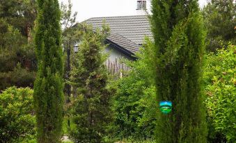 a house with a green roof is surrounded by trees and bushes , with a road sign nearby at Holiday Village