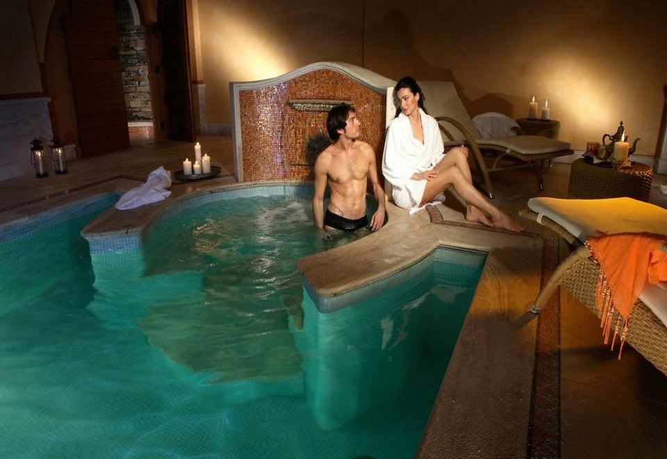 a man and a woman are sitting in a hot tub , relaxing and enjoying each other 's company at Grand Hotel Baia Verde