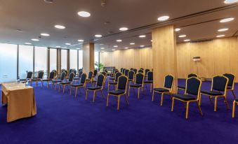 a large conference room with rows of chairs arranged in a semicircle , ready for an event at Sea Porto Hotel