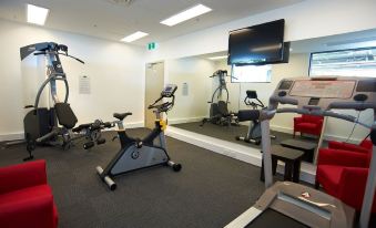 a well - equipped gym with various exercise equipment , including treadmills and stationary bikes , in a modern room with a large window at Quest Werribee