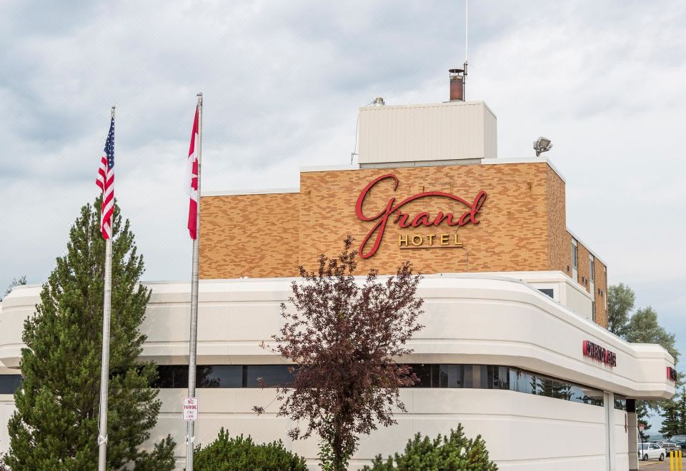 "a hotel building with the words "" grand hotel "" prominently displayed on its exterior , surrounded by flags and trees" at Grand Hotel