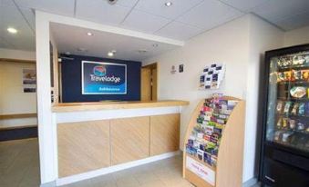 a hotel lobby with a check - in desk and a book display on a counter , where various books are displayed at Travelodge Ashbourne