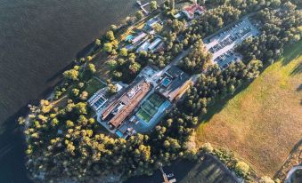 an aerial view of a large house with a pool and tennis courts surrounded by trees near a body of water at Ellery Beach House