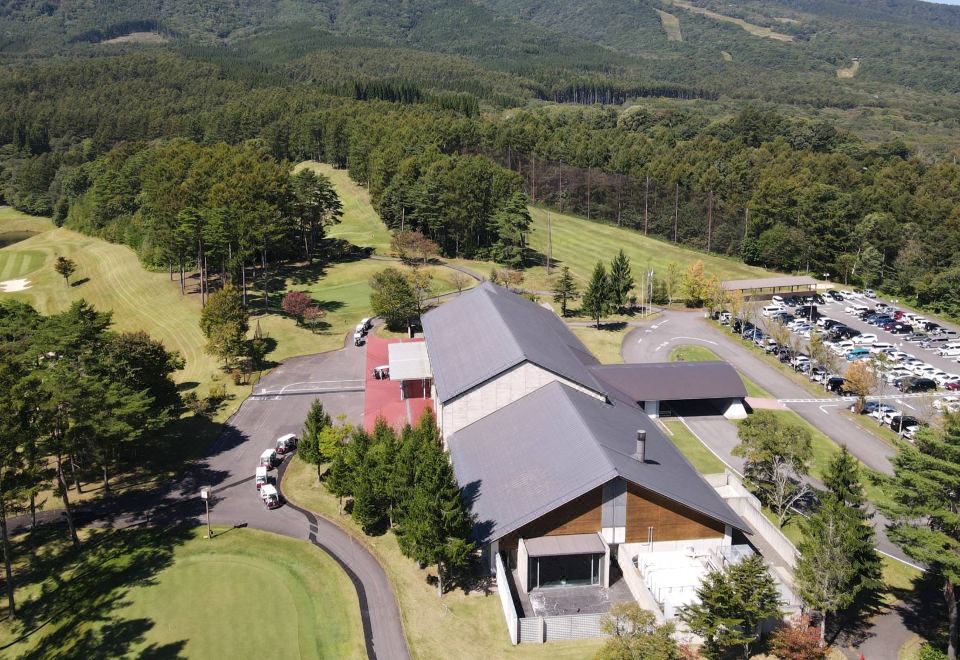 an aerial view of a golf course with a large building and surrounding trees in the background at Arcadia