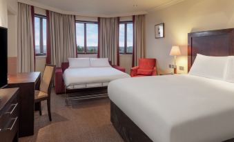 a hotel room with two beds , a window , and a chair , all decorated in white and brown colors at DoubleTree by Hilton Glasgow Westerwood Spa & Golf Resort