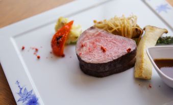 a white plate with a piece of steak , some vegetables , and a sauce on it at Mizno Hotel