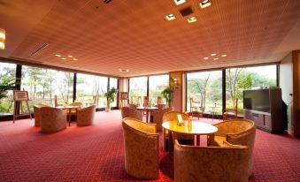 a large , well - lit room with multiple round tables and chairs arranged in an open space at Yufuin Hotel Shuhokan