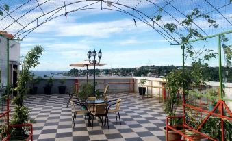 a rooftop patio with a table and chairs , umbrellas , and potted plants , overlooking a cityscape at Syafira Hotel Langgur