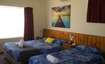 a bedroom with two beds , a nightstand , and a large painting on the wall , creating a cozy and inviting atmosphere at Kadina Village Motel