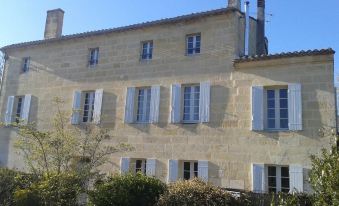 a stone building with blue shutters and a tree in front , under a clear sky at Le Numero 15